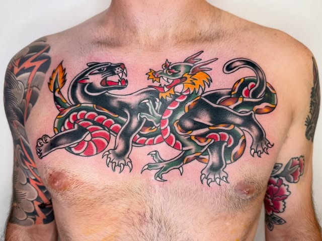 Bold traditional chest tattoo featuring two black panthers and a colorful dragon